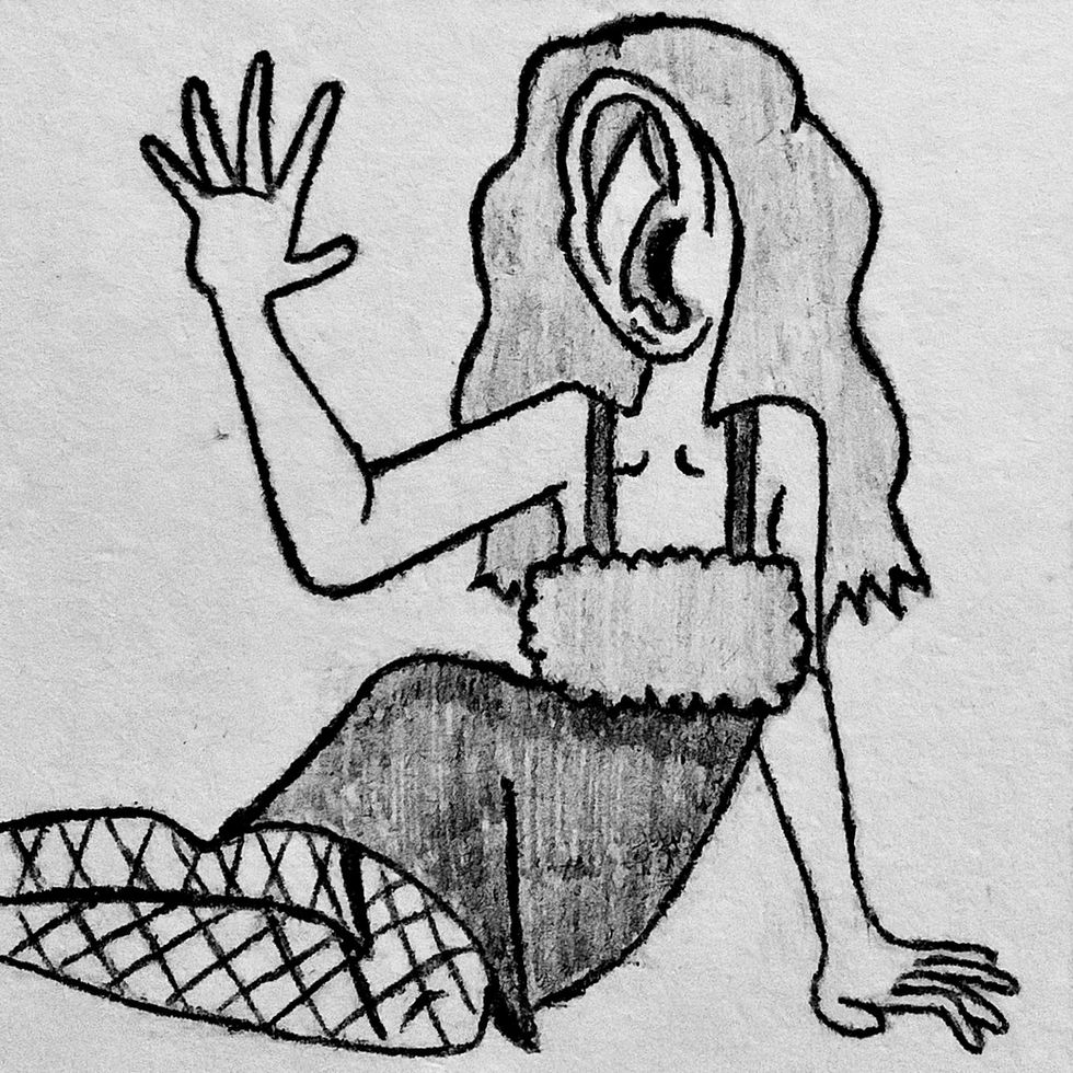 A woman with an ear for a face and wearing a dress laying on the ground as she holds out her hand for a pose.