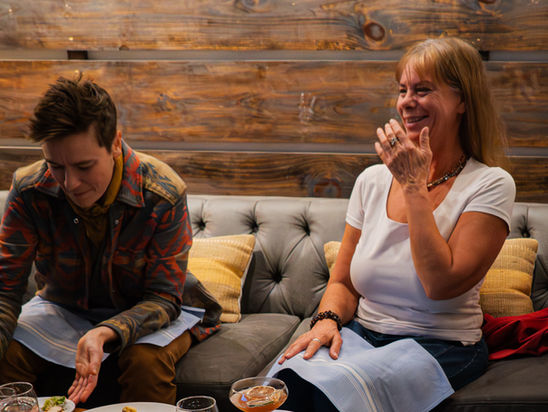people laughing and eating food at a table