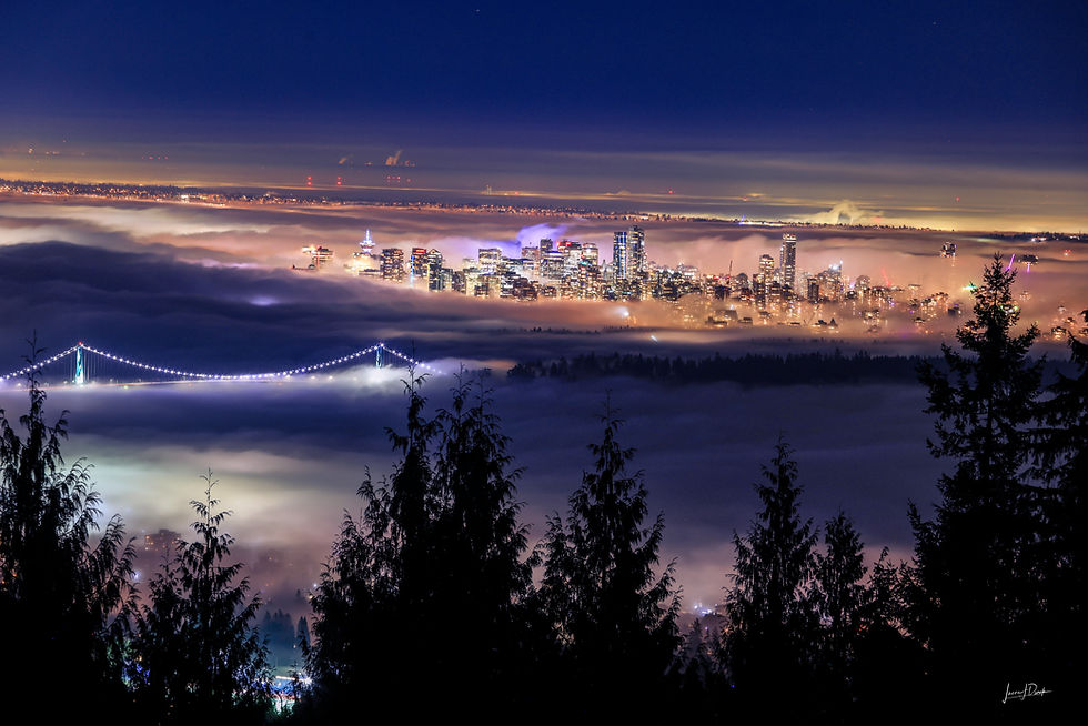 Night photograph of the Vancouver city skyline and the illuminated Lions Gate Bridge emerging from a thick, glowing blanket o