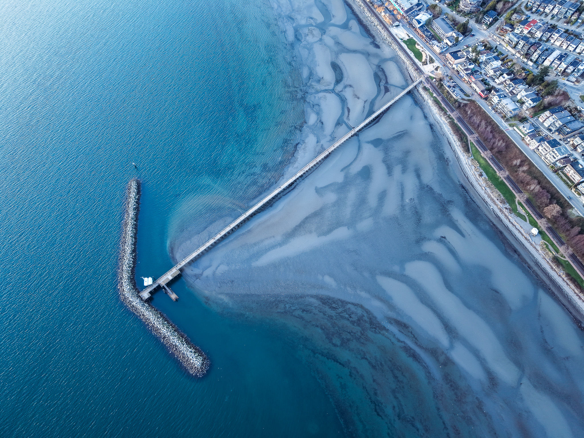 Aerial view of the White Rock Pier and stone breakwater at low tide in Semiahmoo Bay, BC