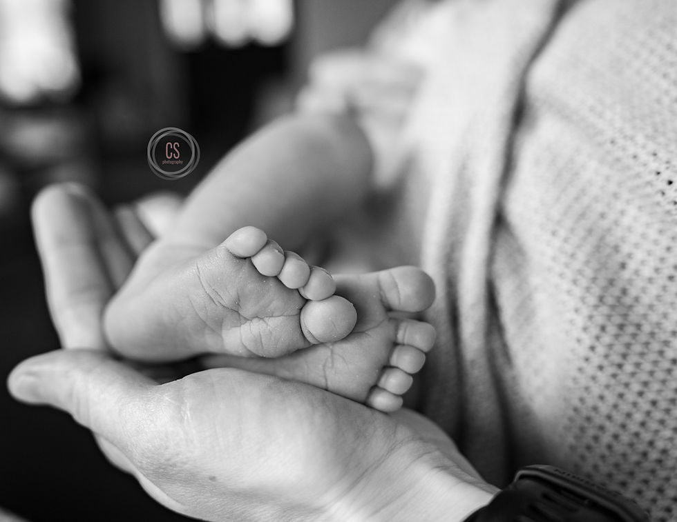 detail photo of baby tiny feet in dad's hands