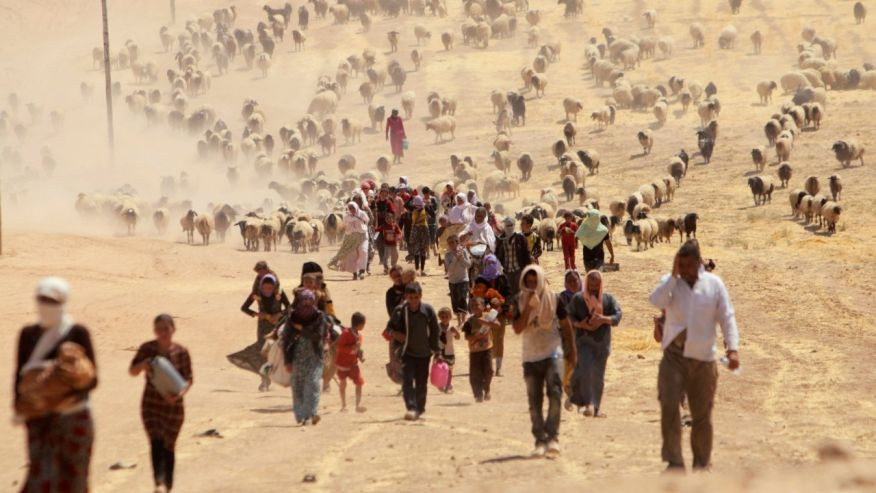 August 10, 2014: Displaced people from the minority Yazidi sect, fleeing violence from forces loyal to the Islamic State in Sinjar town, walk towards the Syrian border, on the outskirts of Mt. Sinjar. (REUTERS/Rodi Said/File )