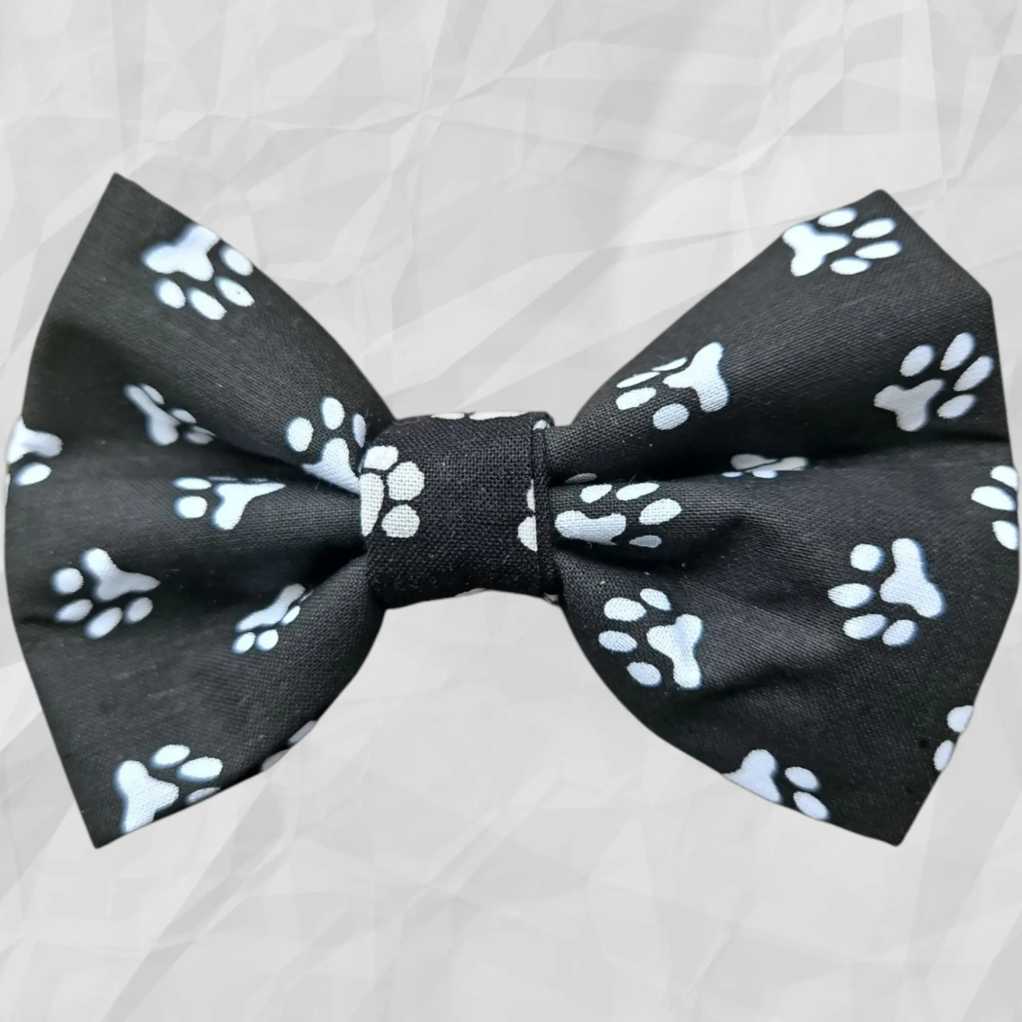 A black pet bow tie with a white paw print pattern.