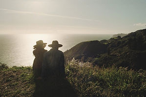 Two people in Stetson hats on a Big Sur ridge above the ocean at golden hour, photo by Titus Haug