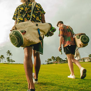 Two friends walking across a field with their bags