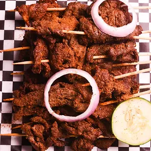 Beef-suya-on-kebab-sticks-with-red-onions-and-cucumber.webp