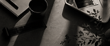 Black and white desk scene with coffee, film negatives and soft shadows