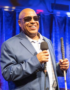 Frank Senior holding a microphone and charming the audience. on stage at Birdland Jazz.