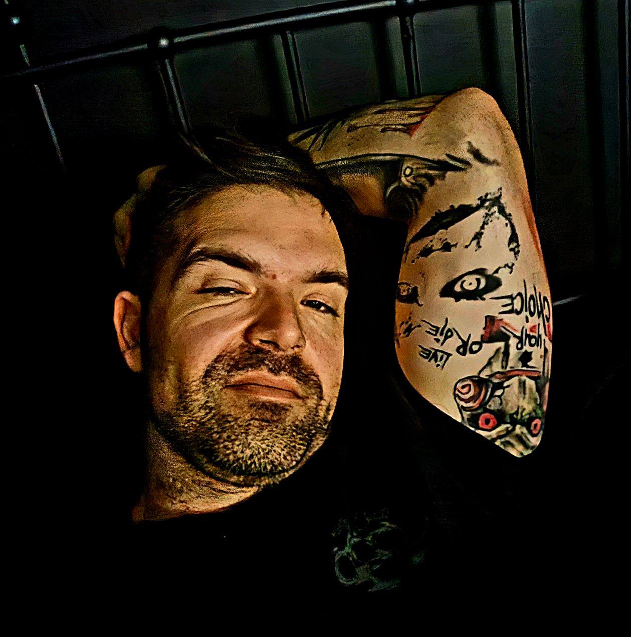 Man with a tattoo on his arm, looking into the camera