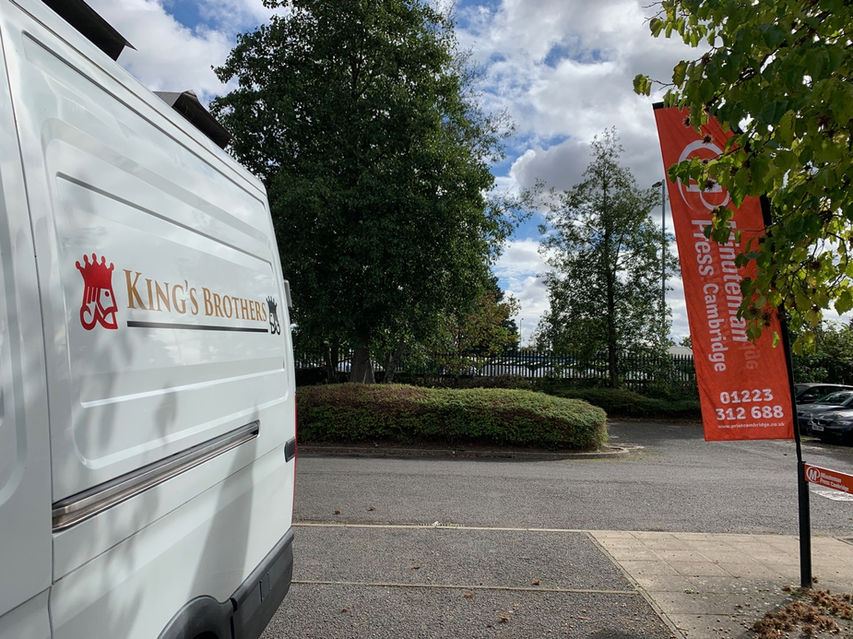 Parked view of King's Brothers completed graphics on white van. 