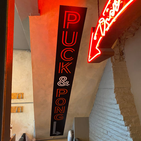 Puck & Pong printed Wall graphic on ceiling above staircase in Cambridge Smokeworks restaurant, neon arrow sign shown in top right