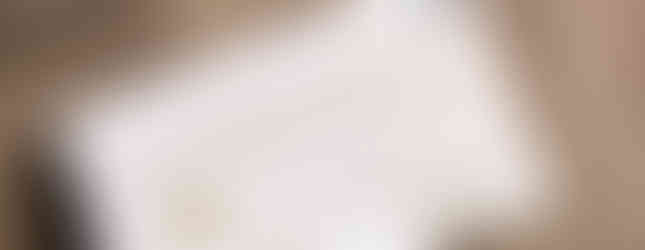 Printed tag shown attached to brown t shirt. Tag detailing premium options for quality t shirt prints Cambridge. Printed in muted gold on white card with black string attachment. 