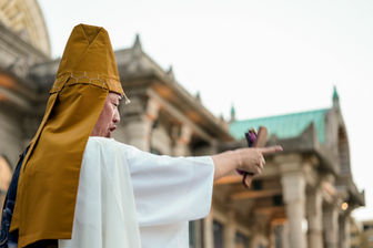 僧侶が寺院を指さす写真