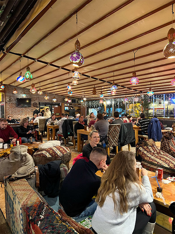 Wide view of the main dining room with traditional lighting and guests at Palatium