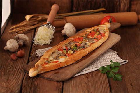 Vegetarian Turkish pide with mushrooms, tomato, peppers, olives and corn