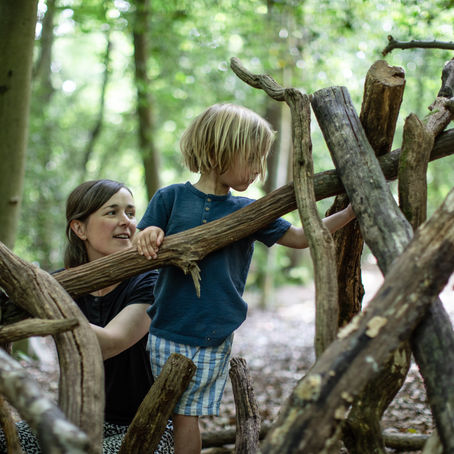 boy building a den with mum during forest family photoshoot in barnet, north london