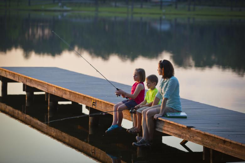 Mother and kids fishing from dock at sunrise on Lake Walter F George with fishing poles visible