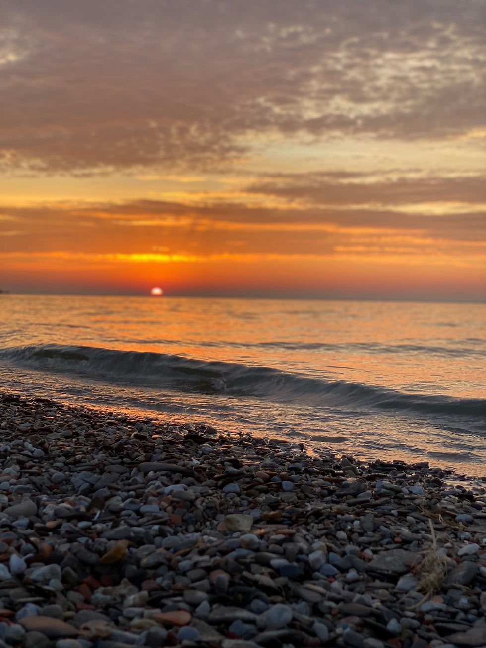 A beautiful orange sunset over ipperwash beach, stones and water.