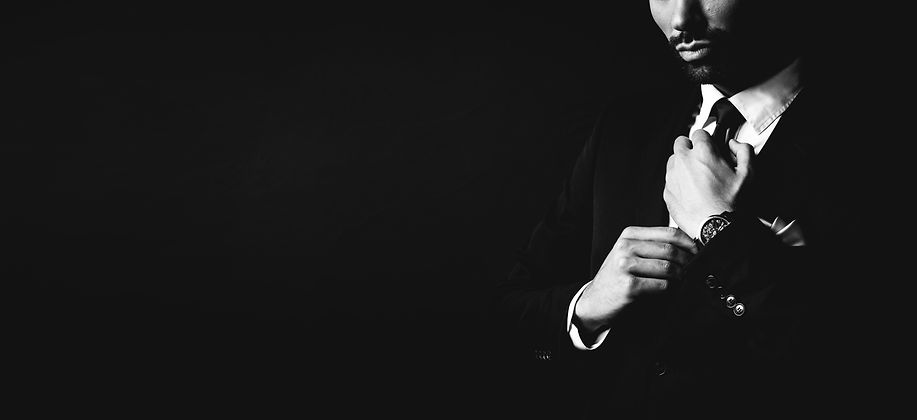 young-man-in-dark-suit-fixing-his-tie-PCWSY5W.jpg