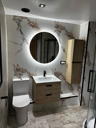 White marble bathroom tiles and backlit round mirror