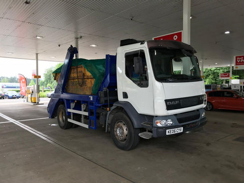 Skip lorry with white cab and yellow skip on back