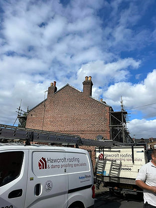 A red brick building with chimneys under a partly cloudy sky.