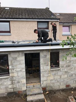 Roofers installing flat roof on extension