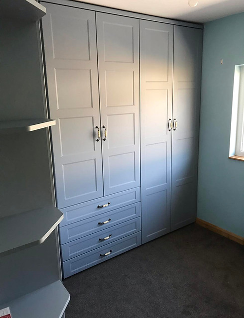 Grey fitted wardrobe with drawers in a bedroom