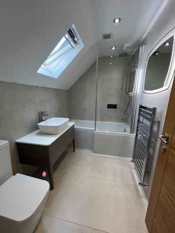 Attic bathroom with a skylight window, white bathtub, and floating vanity setup