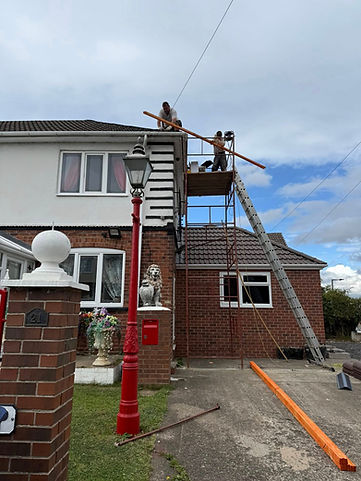 A two-story brick house with scaffolding and ladder on the side