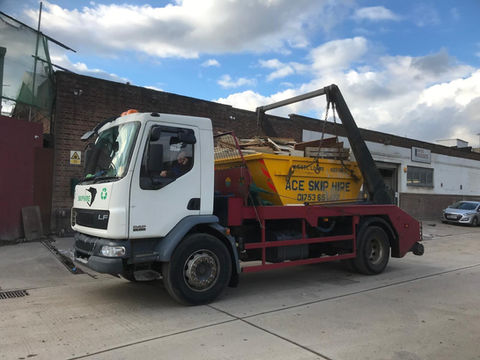 Skip lorry picking up skip