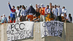 Presos exibindo faixas com "PCC Paz Justiça Liberdade" e "Contra a Opressão" durante rebelião, ilustrando a ascensão inicial.