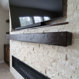 TV above a textured fireplace surround with a dark wood mantel.