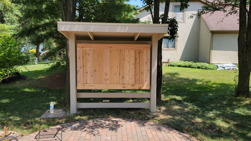Finished wooden exterior TV enclosure installed in a backyard.
