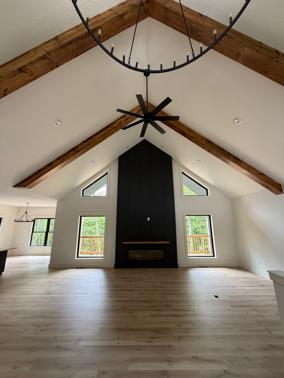 Wood beams on a vaulted ceiling above a dark paneled fireplace wall.