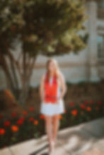 Texas Tech senior under a tree with red flowers