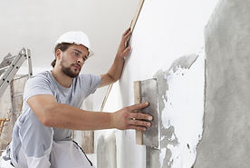 Hands man plasterer construction worker at work with trowel, plastering a wall, closeup.jp