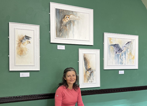 Rachel Singleton at Brantwood in front of a wall full of her bird paintings