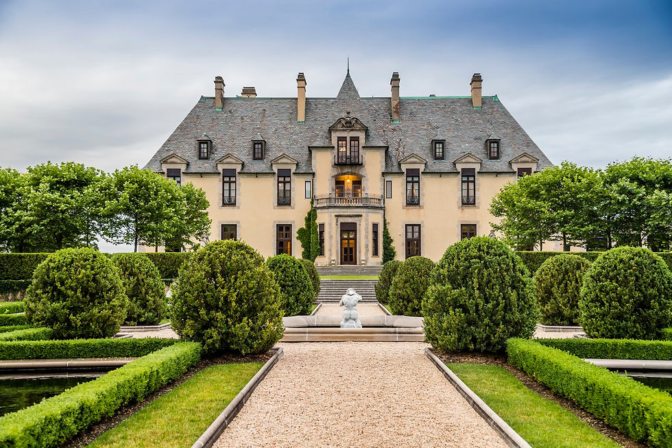 NYC wedding DJ Grand stone mansion with slate roof behind manicured hedges, gravel path, and fountain under a calm blue sky.