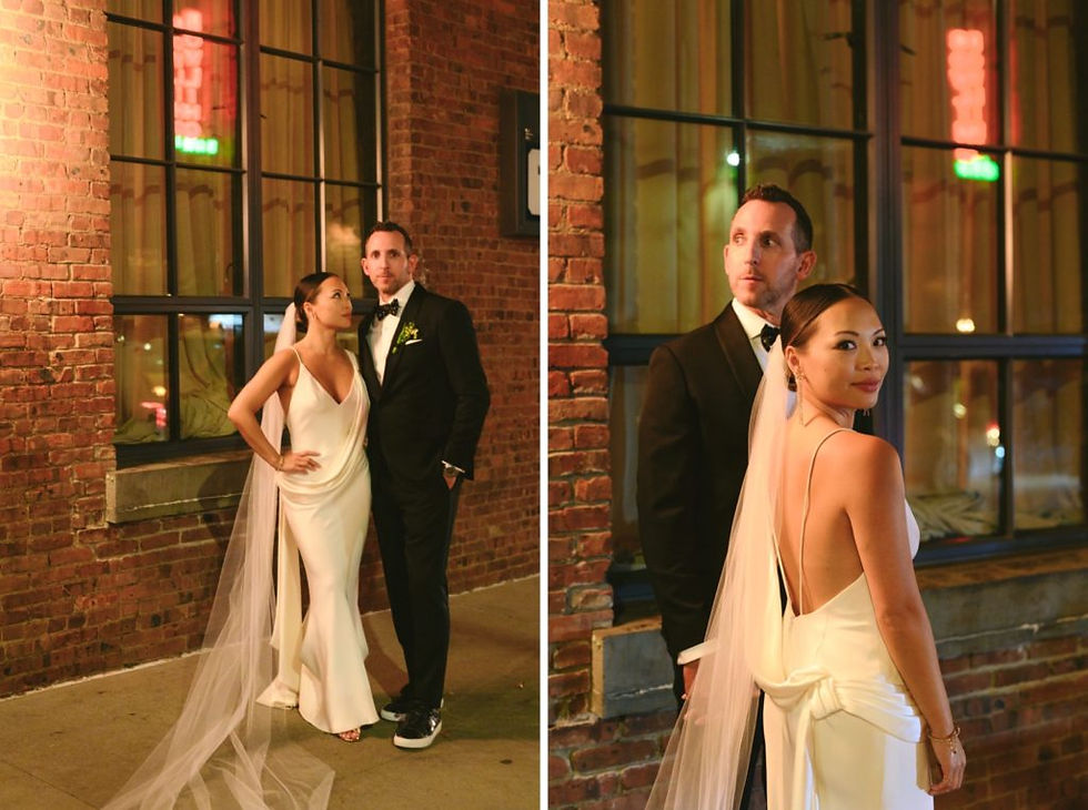 nyc weddind dj Bride in white gown and veil poses with groom in black tuxedo against a brick wall at night, looking elegant.