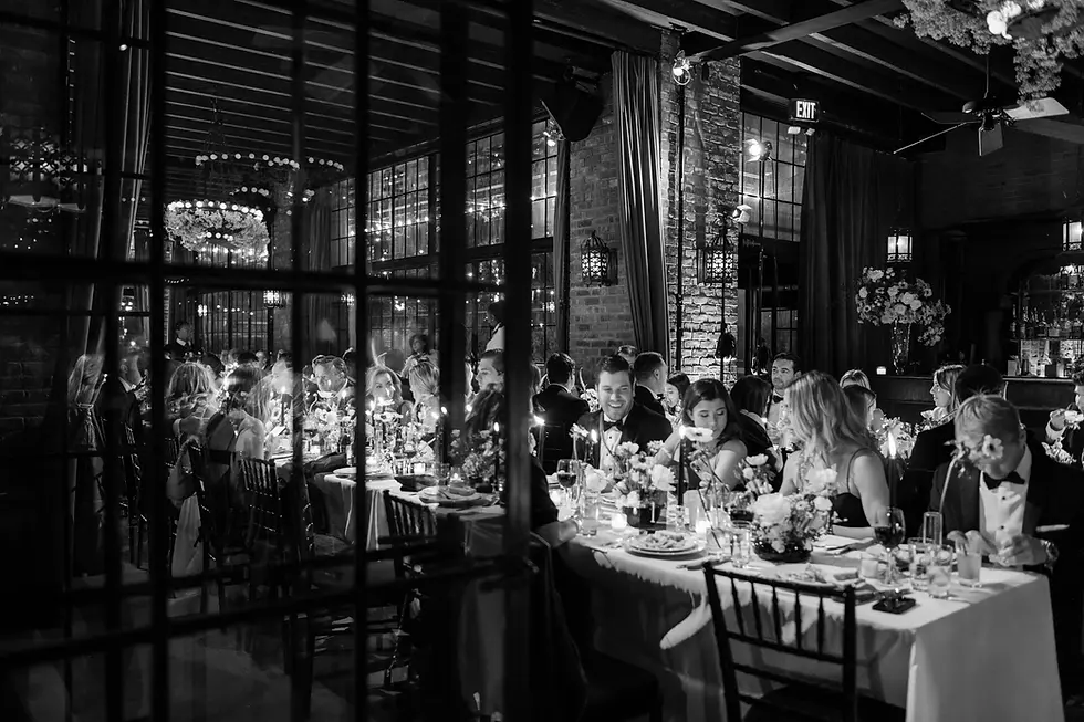 The Bowery Hotel NYC Wedding DJ Elegant black-and-white wedding reception with guests dining at candlelit tables, floral centerpieces, and an EXIT sign.