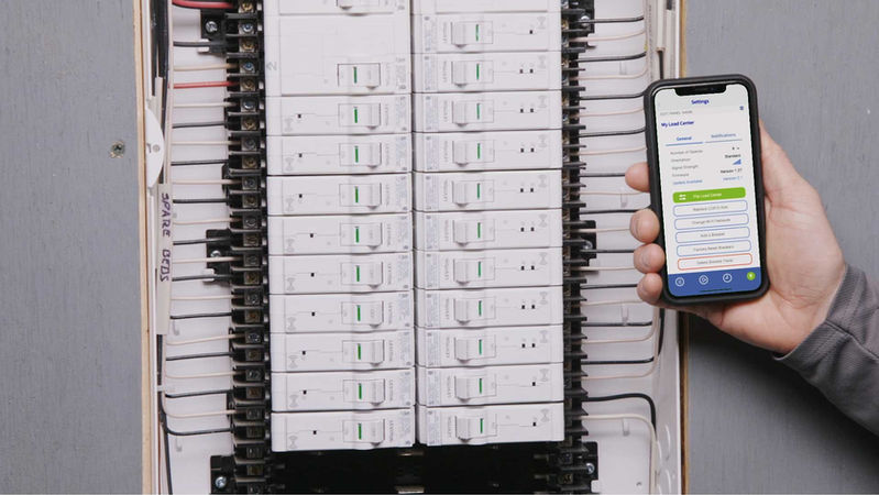 A smart electrical panel beside a phone showing its controls