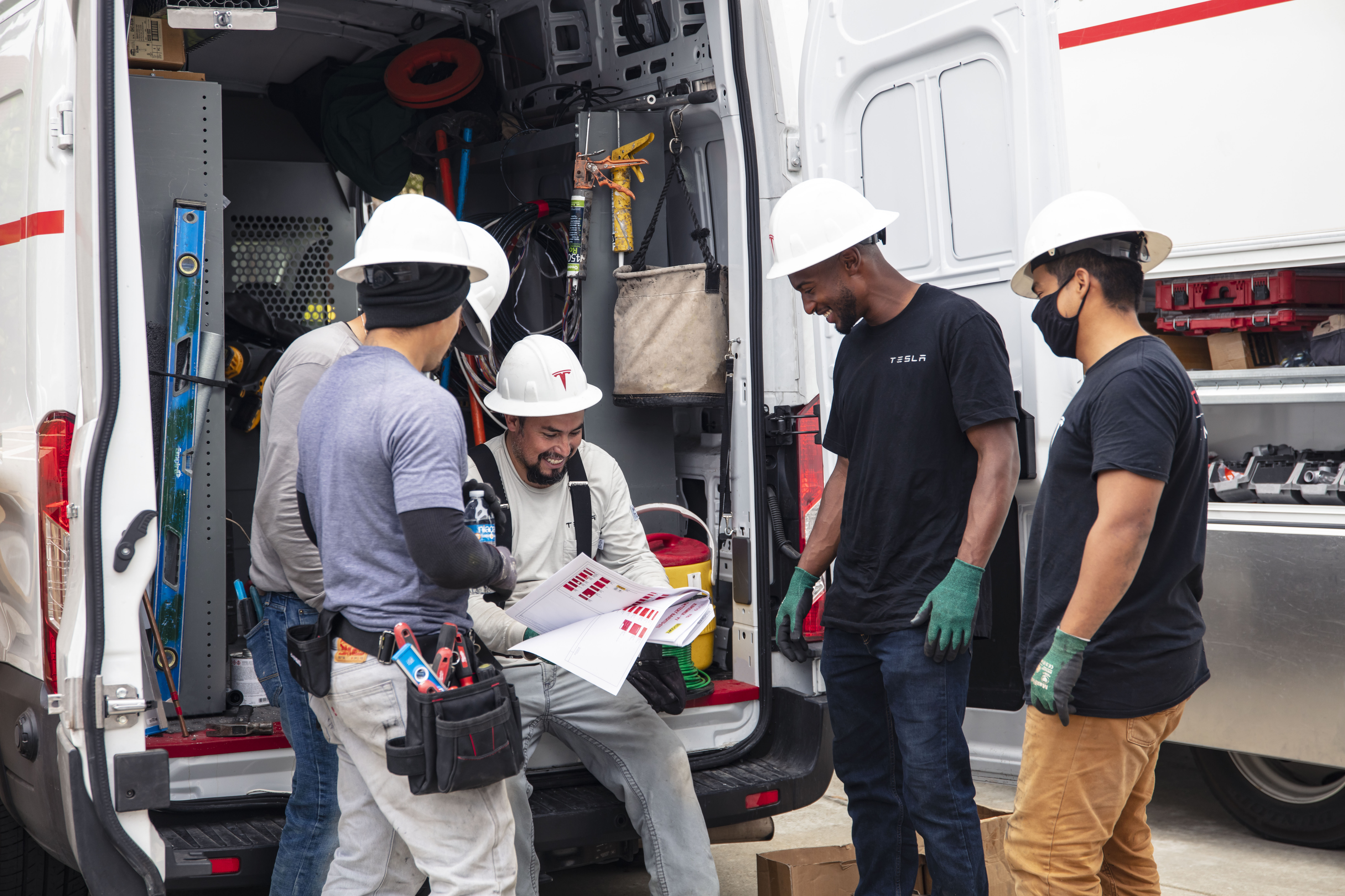 Contractors reviewing project plans beside a work van