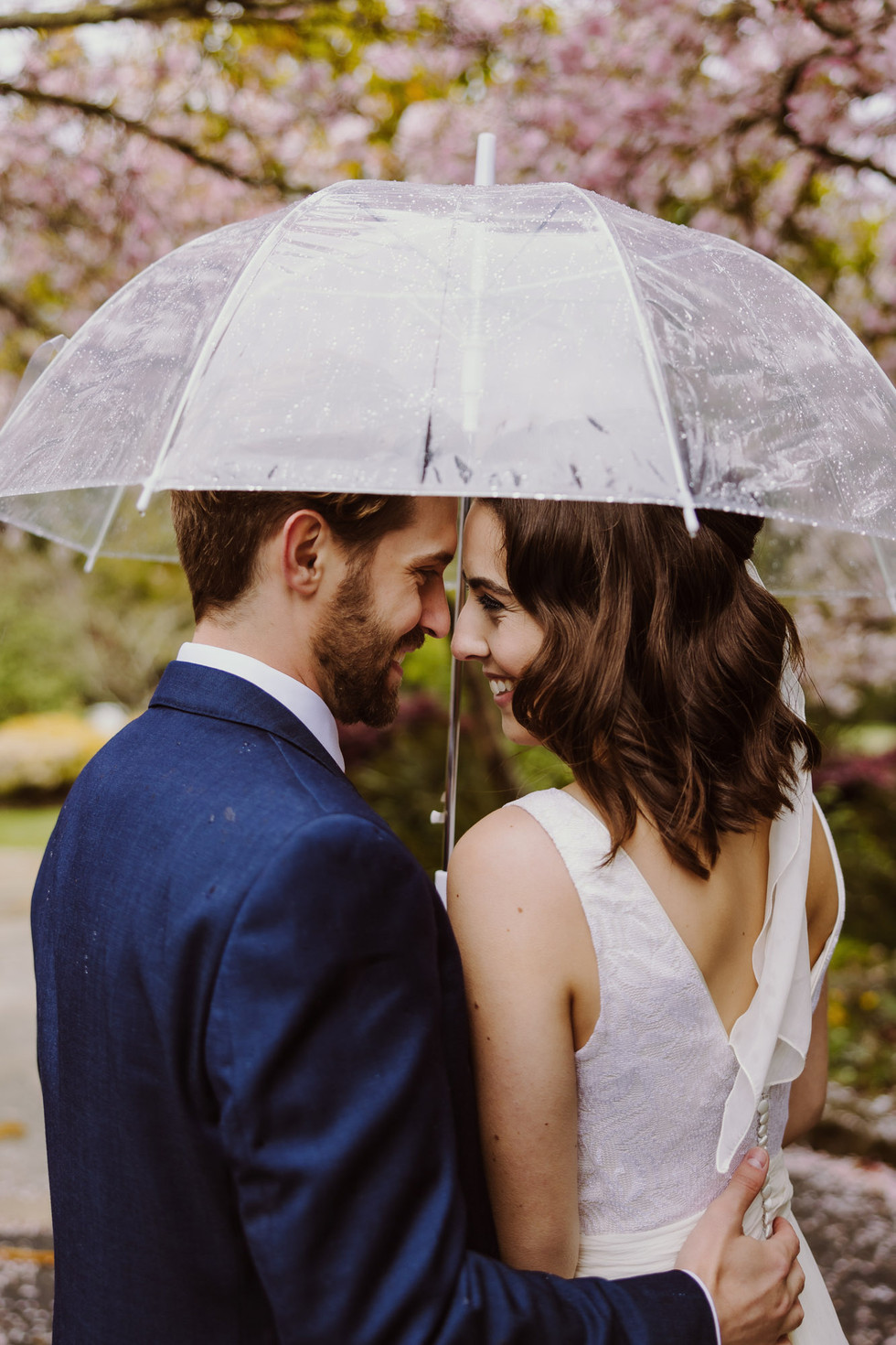 Bride and groom under cherry blossoms at the Brazilian Room in Berkeley, CA on a rainy wedding day