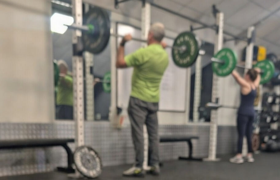 Two lifter at a rack doing an overhead press