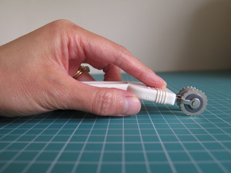 Holding the Clover double tracing wheel in the hand, showing the ergonomic angled handle