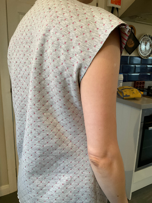 Side back view of toile of Tilly and the Buttons Stella Hoodie in grey sweatshirt fabric showing folds with the right arm down