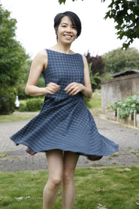 Asian female in a dark blue sleeveless knee length Lilou dress with white checks, twirling around facing the camera