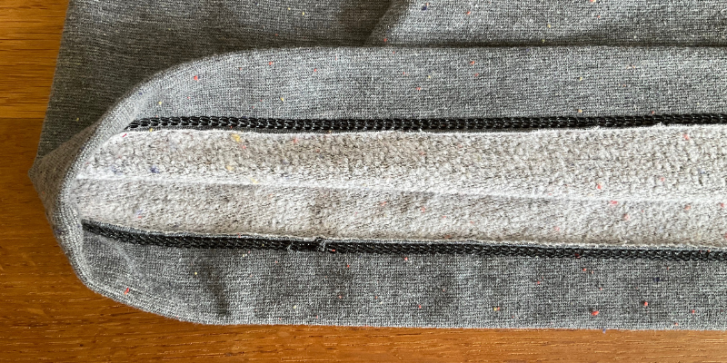 Inside the hem of the Tilly and the Buttons Stella Hoodie showing neat coverstitching with black woolly nylon, on grey multi fleck sweatshirt fabric from Guthrie&Ghani