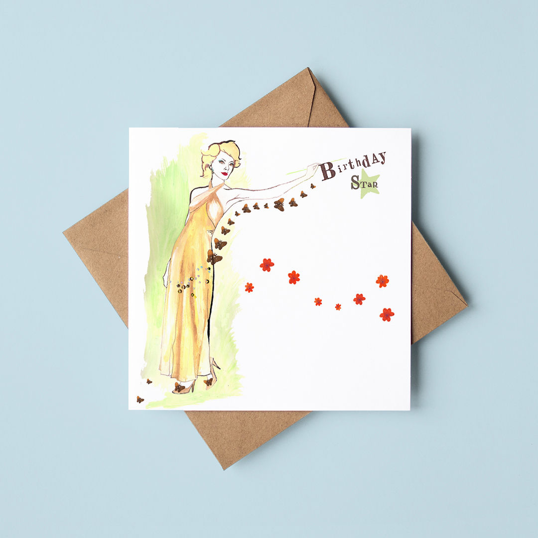 A white square illustrated greeting card of a glamorous female figure. Rests on a brown envelope with grey background.